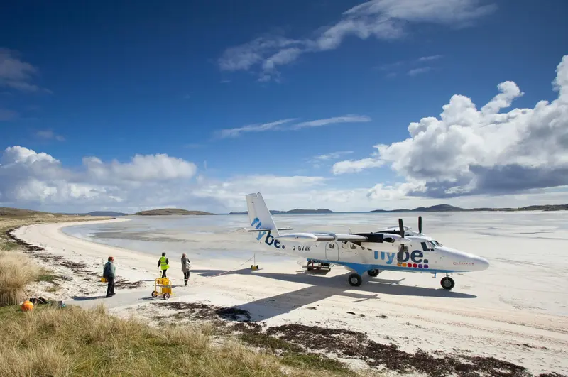 A turboprop plane stands on the sandy beach runway of Barra Airport.