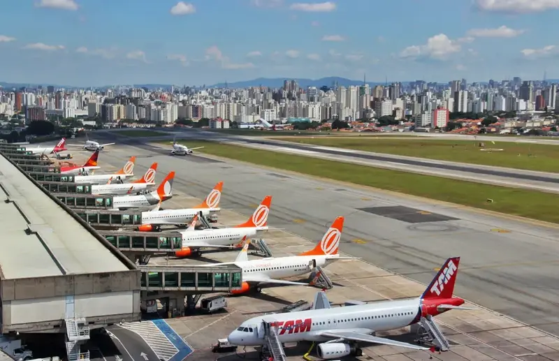 A row of planes at Congonhas Airport with the cityscape in the background.