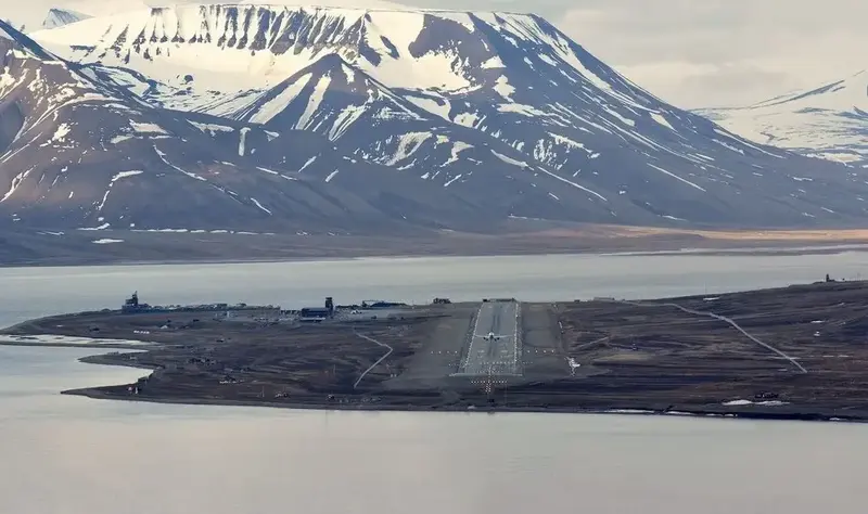 Remote Svalbard Airport runway fringed by snow-capped mountains.