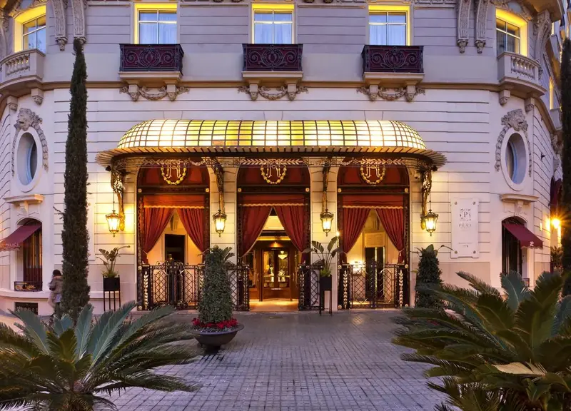 Luxurious Hotel Palace GL entrance with ornate awning and red curtains in Barcelona.