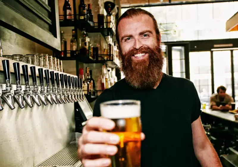 Beaming bartender with beer celebrates St. Patrick's Day.