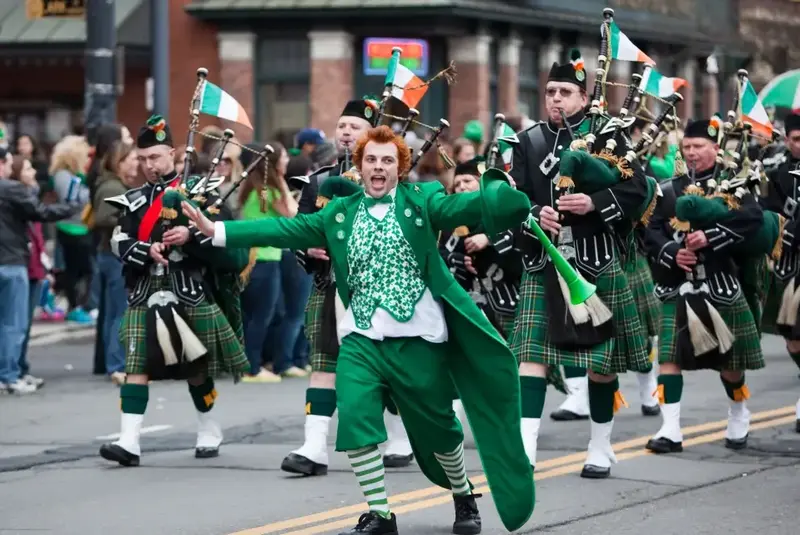 Lively St. Patrick’s Day parade with bagpipers and a jester in green.