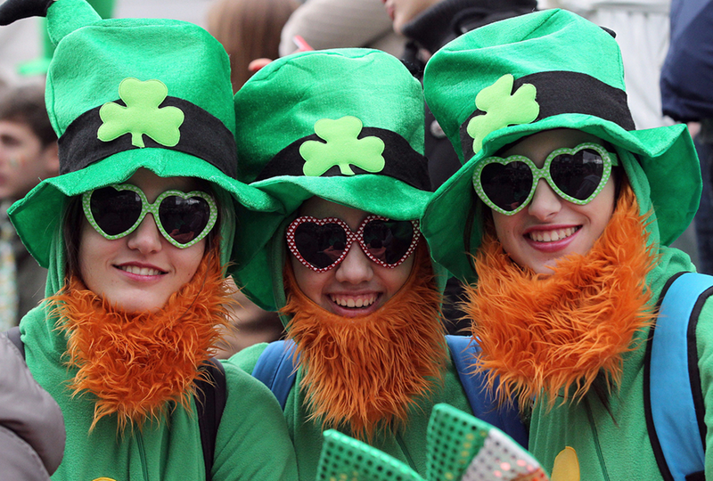 Smiling trio in green hats and beards celebrating the holiday.