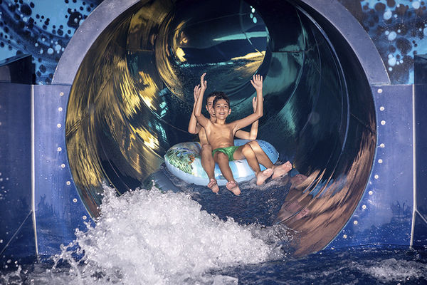 Boy in tube slide splashing water at a fun park.
