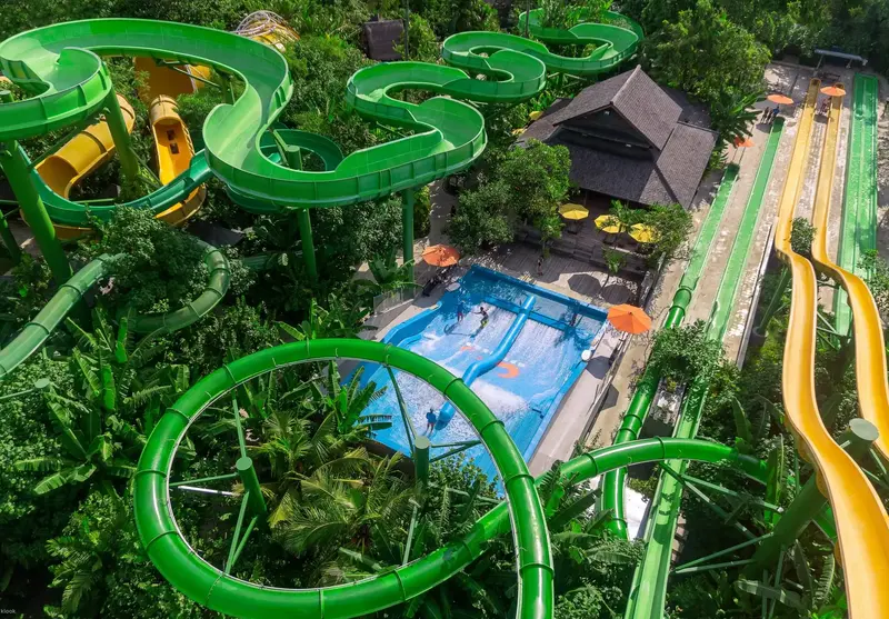 Aerial view of serpentine slides amidst tropical greenery.
