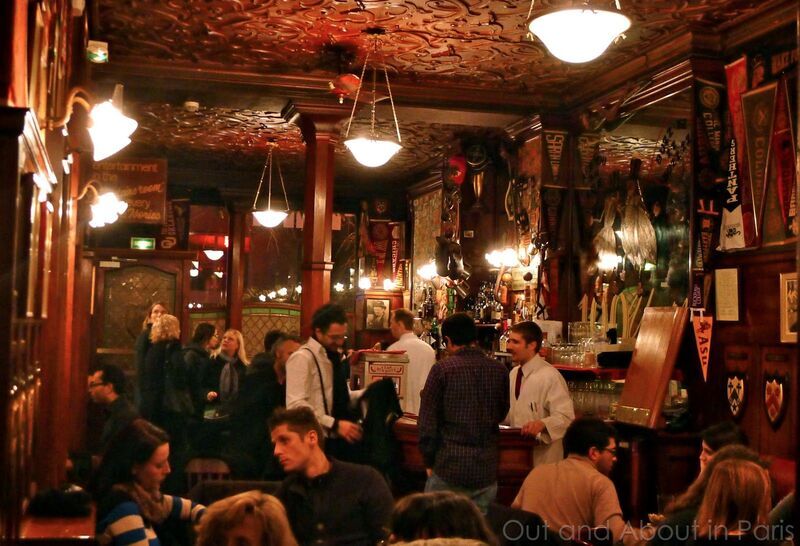 The classic interior of Harry's Bar in Paris, bustling with a diverse crowd enjoying the legendary establishment's ambiance. Rich wooden decor and vintage pennants line the walls, while patrons engage in lively conversation, reflecting the bar's storied history as a birthplace of the Bloody Mary, a fixture in the narrative of the best bars and clubs in Paris.