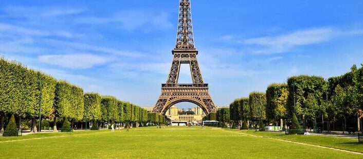 Sunny view of the Eiffel Tower with green lawns of Champ de Mars.