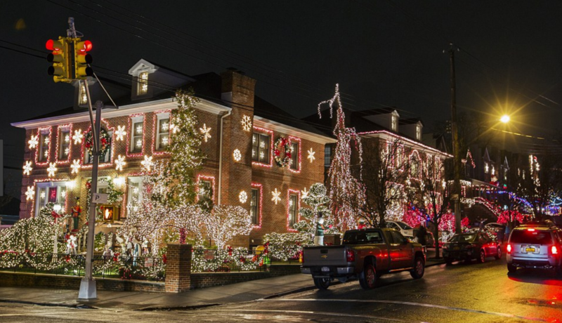 A residential street in Dyker Heights, New York, festooned with elaborate Christmas lights and decorations, showcasing a popular Christmas activity in the city.