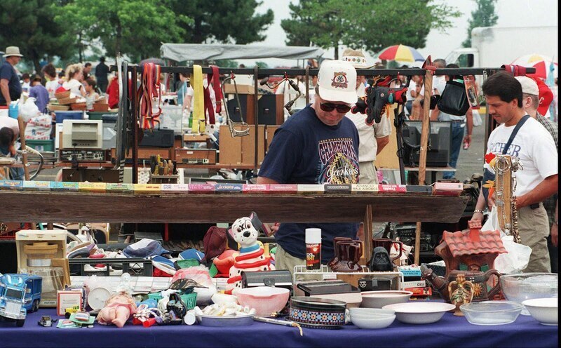 Shoppers peruse an assortment of items at a bustling outdoor flea market, with tables laden with vintage goods, collectibles, and quirky finds, epitomizing the local shopping experience in New York.