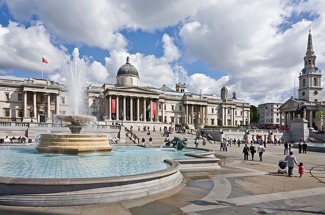 The bustling Trafalgar Square in London with its iconic fountains and the National Gallery in the background.