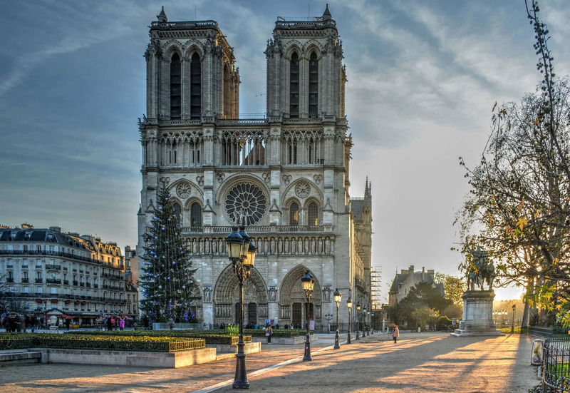 Sunset view of Notre Dame Cathedral in Paris, with shadows stretching over the square.