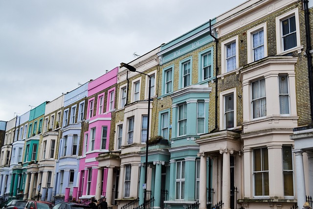A row of vibrant, multicolored Victorian townhouses under an overcast sky in Notting Hill, a quintessential example of London's best neighborhoods, renowned for its unique architecture and cultural flair.