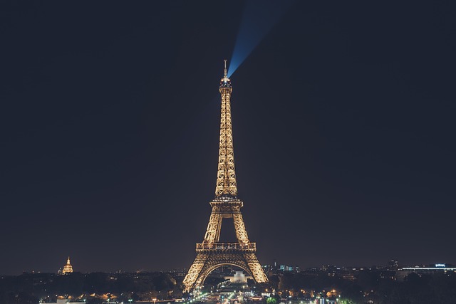 Illuminated Eiffel Tower at night with searchlight.