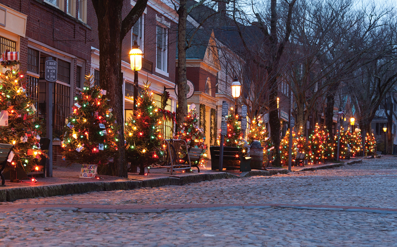  A row of Christmas trees lit with colorful lights lining an old cobblestone street in New York at dusk, embodying the quaint and festive activities available during the holiday season.