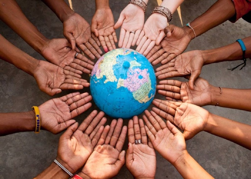Hands of diverse people circling a globe.