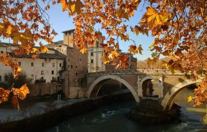 Autumn leaves framing a bridge over Tiber in Rome.
