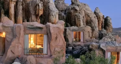 A unique hotel with rooms integrated into rocky cliffs at dusk.