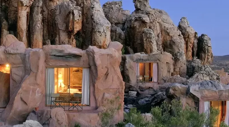 A unique hotel with rooms integrated into rocky cliffs at dusk.